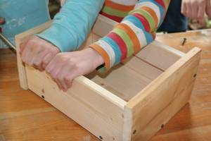 Kind bastelt Nisthilfe aus Holz